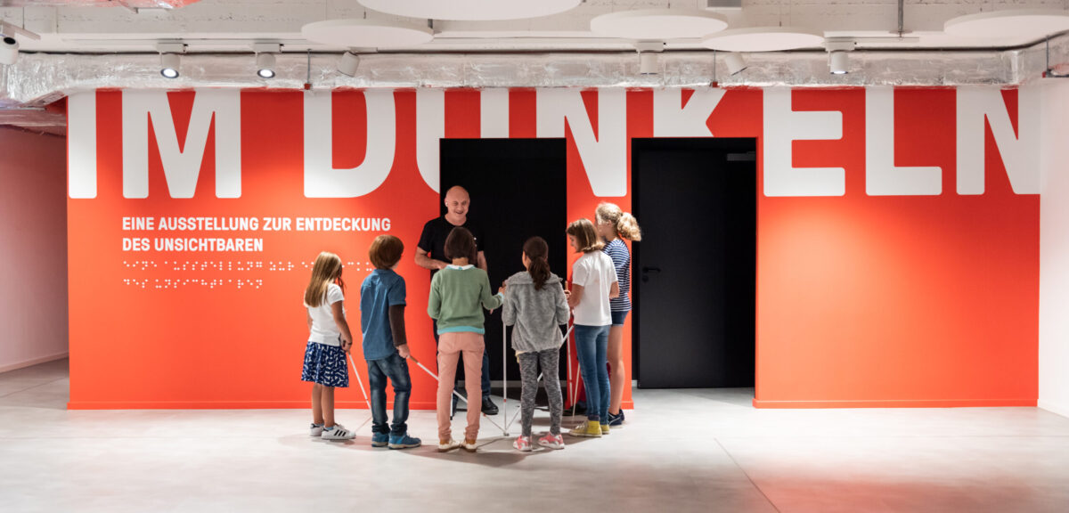 The museum entrance with a group of children standing around a blind man