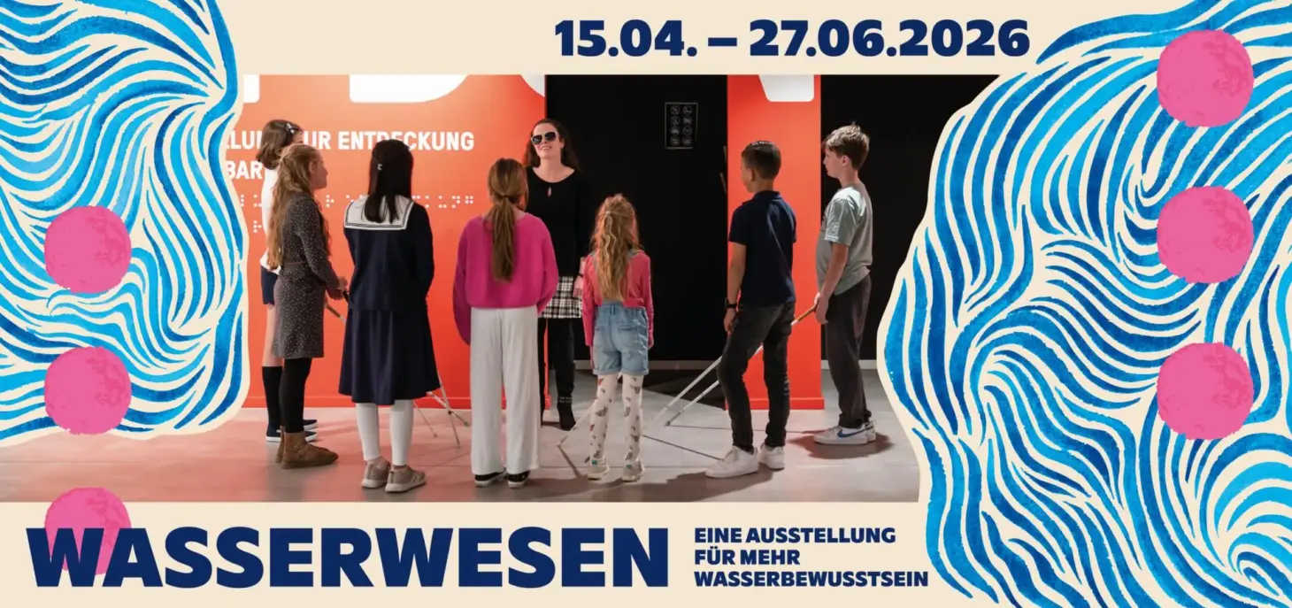 In the center, you can see a woman with long brown hair and sunglasses. In front of her, arranged in a semicircle, are several children holding white canes. You can only see their backs. Behind the woman, you can see the museum’s red wall and two dark entrances. At the right and left edges of the picture, there are blue, flowing lines that curve around and into one another like water. There are also three pink dots on each side. At the top and bottom of the picture are the key details for the exhibition “Water Creatures” (April 15–June 27, 2026).